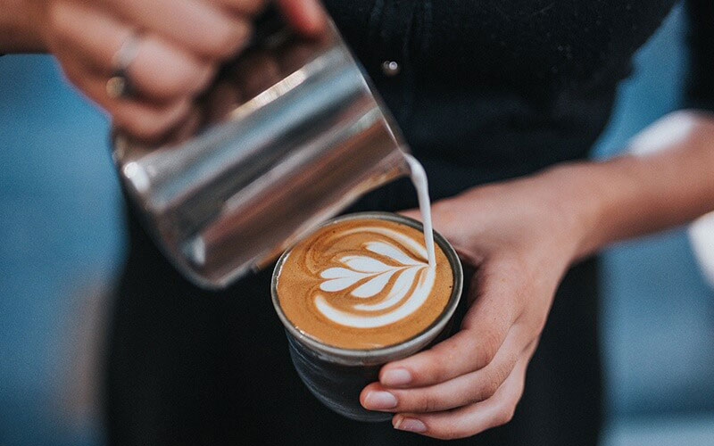 Winci - Một người pha chế Cà phê Flat White bằng cách rót cà phê với latte art.